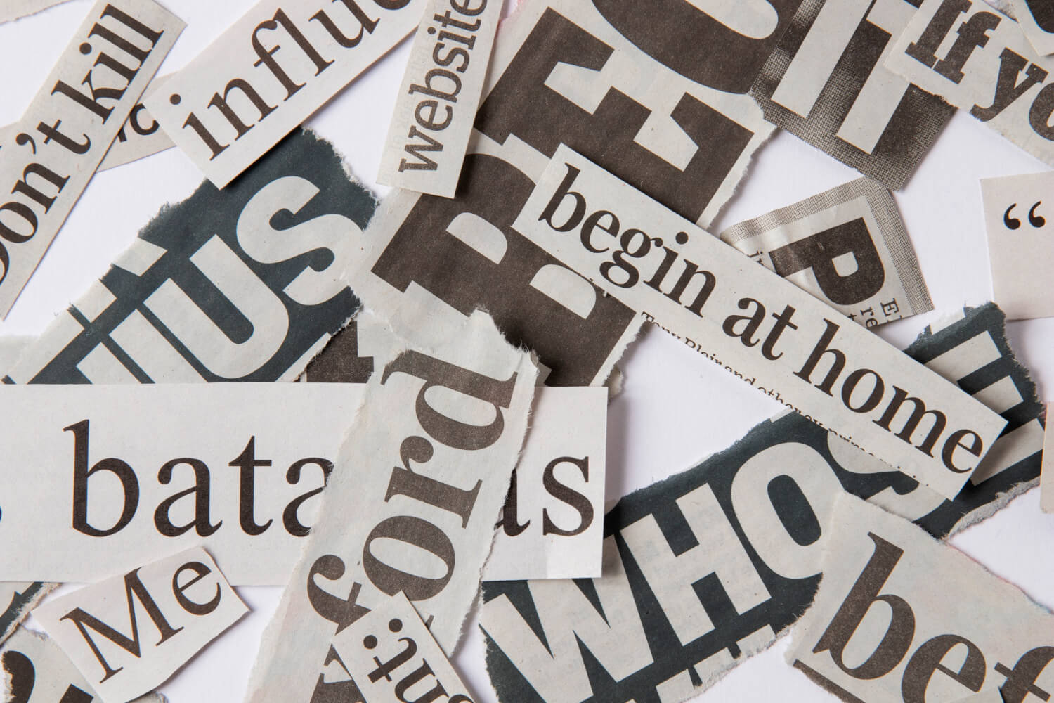 Un primer plano muestra una colección de recortes de periódicos con varias palabras y fragmentos de texto desorganizados, sobre un fondo blanco. Se pueden leer palabras como 'begin at home', 'website', 'influence', y fragmentos de titulares y texto. La imagen ilustra el concepto de organizar la información y la jerarquía, que es fundamental para el subcapítulo 'Entender la jerarquía de los encabezados (H1-H6)' dentro del blog 'Uso estratégico de encabezados y jerarquía del contenido'. Representa el caos de la información sin estructura, y resalta la necesidad para los emprendedores digitales de organizar su contenido de manera clara y jerárquica para que los motores de búsqueda como Google puedan entender su relevancia y posicionarlo de manera efectiva a largo plazo.